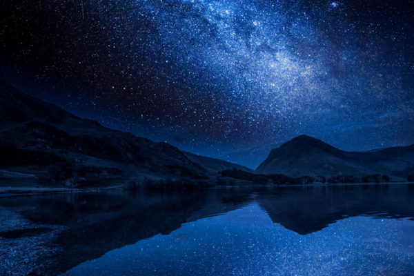 Estrelas refletidas em lago de águas calmas durante a noite